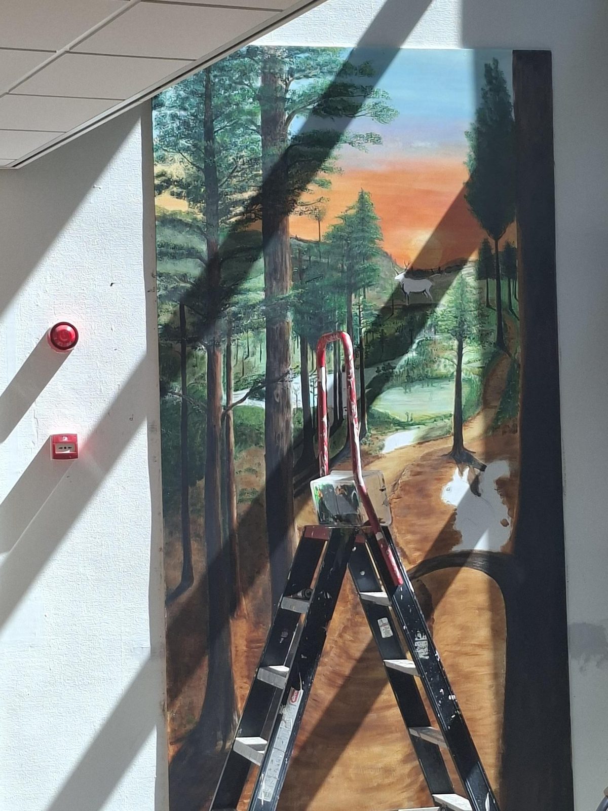 Detail van de muurschildering: een wit hert op een open plek bij zonsondergang